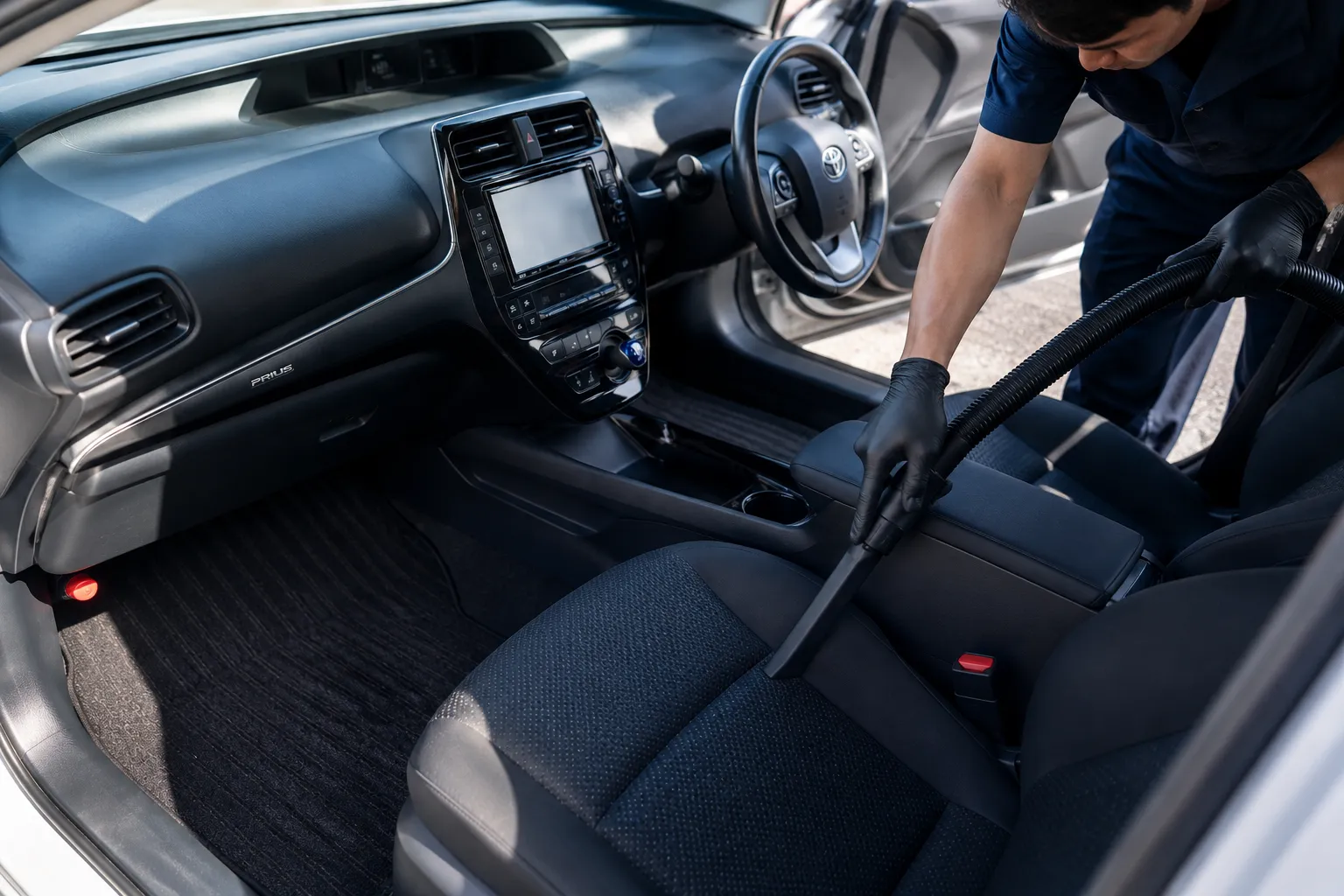 車内を掃除機で吸い上げる様子。シートやコンソール周りのホコリ・砂を丁寧に除去します